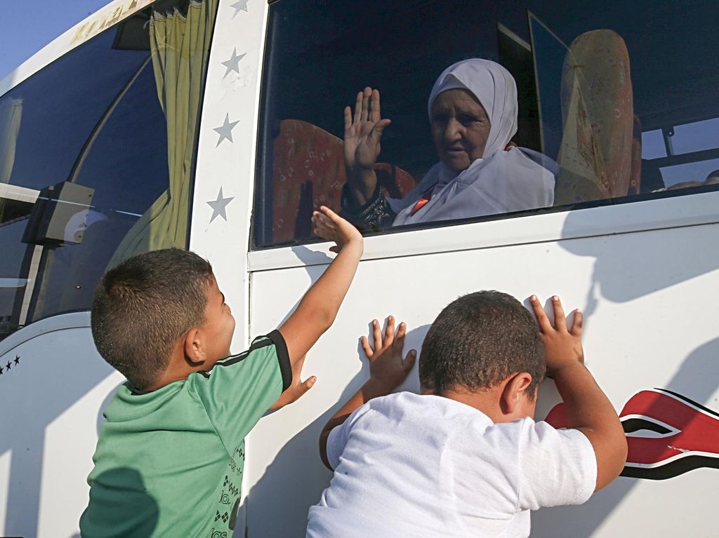 A Palestinian Muslim pilgrim waves to her relatives as she sits in a bus at the Rafah border crossing between the Gaza Strip and Egypt. AFP