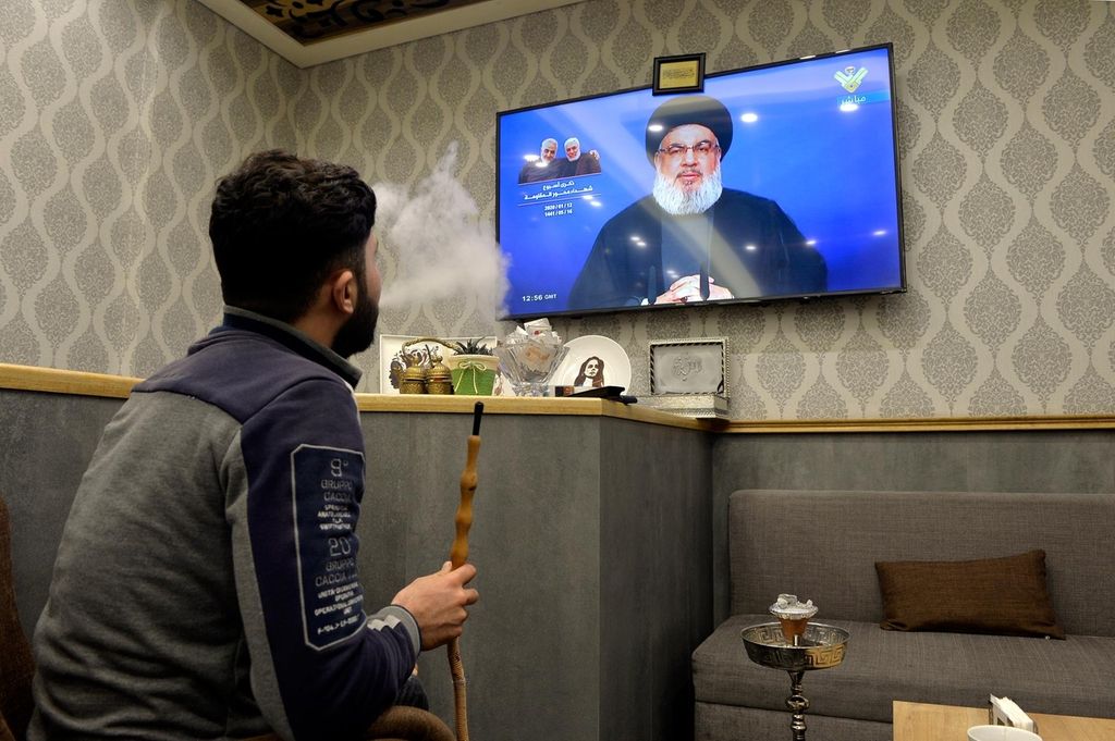 epa08122250 A Lebanese man smokes water pipe as he watches the speech of Hezbollah leader Hassan Nasrallah on a television screen at a cafe to mark the one-week death of slain the Iranian Revolutionary Guards Corps (IRGC) Lieutenant general and commander of the Quds Force Qasem Soleimani in Beirut, Lebanon, 12 January 2020. The US Pentagon announced that Iran's Quds Force leader Soleimani and Iraqi militia commander Abu Mahdi al-Muhandis were killed on 03 January 2020 following a US airstrike at Baghdad's international airport. EPA/WAEL HAMZEH