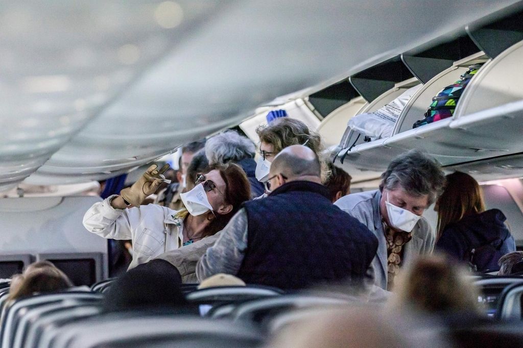 Passengers, some wearing protective face masks, aboard an EgyptAir flight bound for Cairo stow away their luggage in the overhead compartments prior to take-off from Luxor International Airport in southern Egypt, on March 13, 2020. / AFP / Khaled DESOUKI