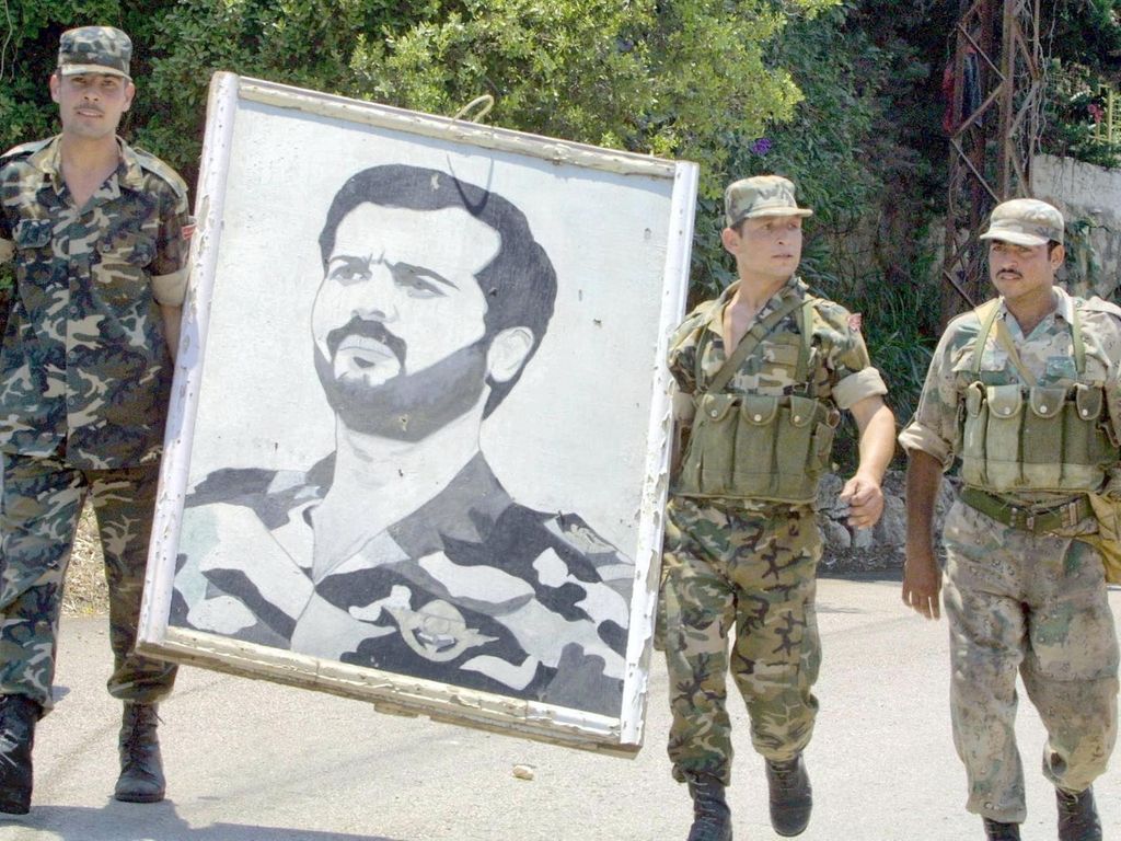 Syrian soldiers carry a portrait of Syrian president Bashar al-Assad's late brother, Bassel, near Beirut on 14 June 2001. AFP