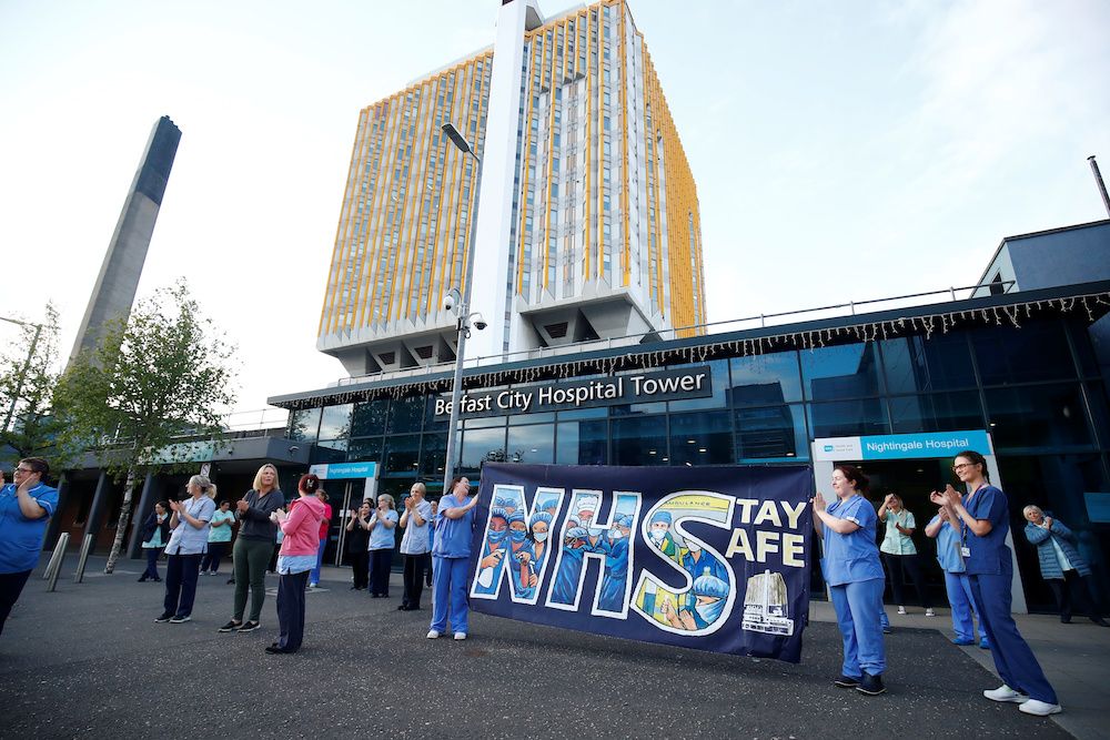 NHS workers with a banner react at the Nightingale Hospital during the Clap for our Carers campaign in support of the NHS, following the outbreak of the coronavirus disease in Belfast, Northern Ireland, May 7, 2020. — Reuters pic
