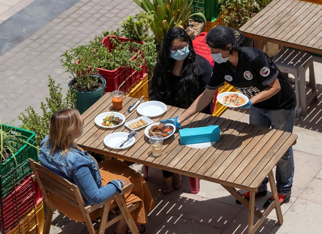 People have lunch at a cafe in Jumeirah Lake Towers, Dubai. A few restaurants are now open to children under 12 and those above 60. Chris Whiteoak / The National