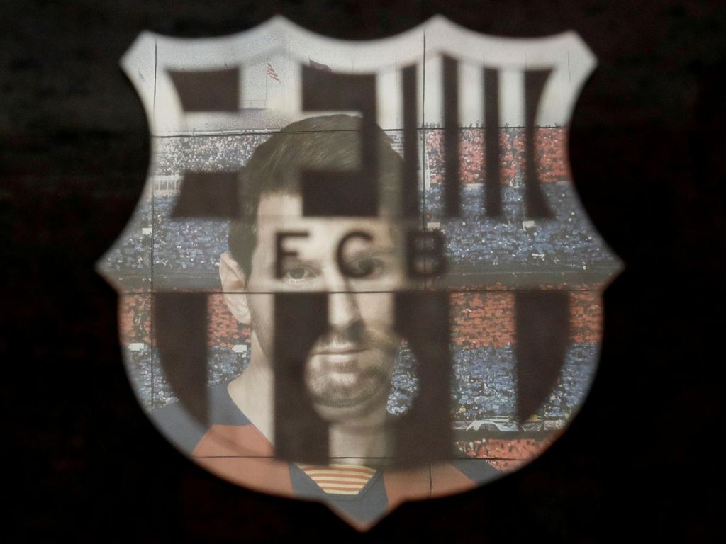 FILE PHOTO: Soccer Football - La Liga Santander - FC Barcelona v Real Sociedad - Camp Nou, Barcelona, Spain - March 7, 2020 A picture of Lionel Messi is reflected in the Barcelona emblem outside the stadium before the match REUTERS/Albert Gea/File Photo