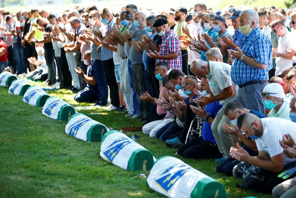 People pray near coffins at a graveyard during a mass funeral in Potocari near Srebrenica, Bosnia and Herzegovina July 11, 2020. — Reuters pic