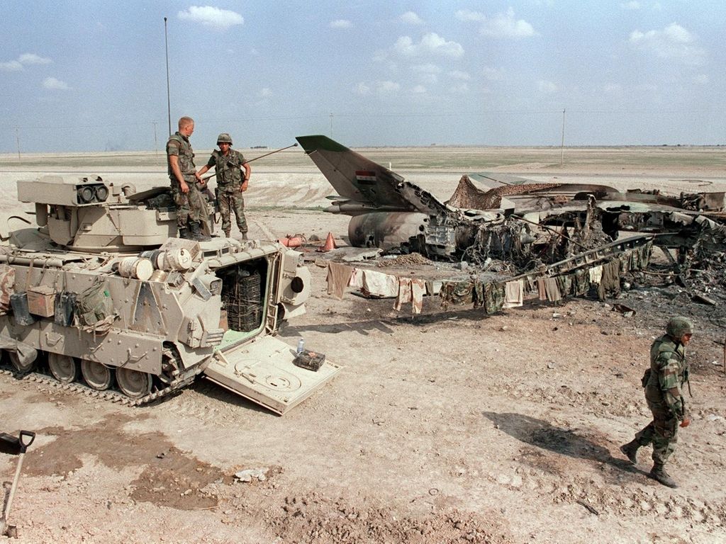 US soldiers at the Nasiriyah air base in Iraq, 300 kilometres south of Baghdad, beside a destroyed Mig-22. AFP