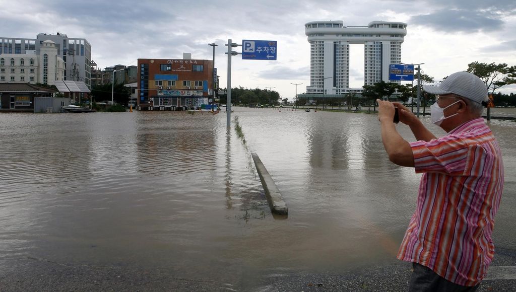 A man takes a photo of a submerged car park in Gangneung, South Korea. Yonhap via Reuters