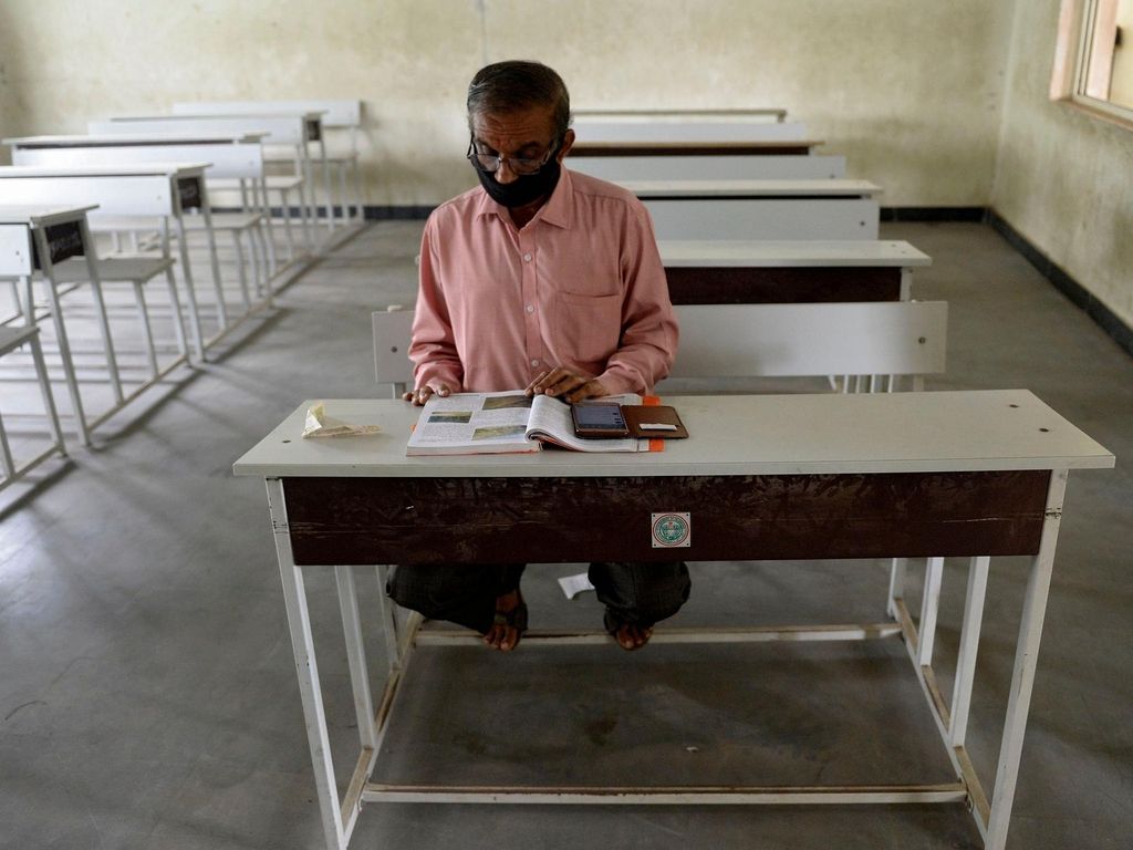 A teacher sits in an empty classroom as he prepares for online teaching at a government high school in Hyderabad on September 21, 2020, after the state government allowed 50 percent of staff at schools and colleges to resume duties for tele-counselling and online teaching amid Covid-19 coronavirus pandemic. AFP