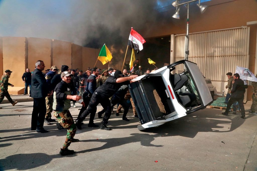 FILE - In this Dec 31, 2019 file photo, pro-Iranian militiamen and their supporters damage property inside the U.S. embassy compound, in Baghdad, Iraq. The Trump administration has signaled it could close its diplomatic mission in Baghdad if measures are not taken to control rogue armed elements responsible for a recent spate of attacks against U.S. and other interests in the country, Iraqi and U.S. officials said Monday, Sept. 28, 2020. (AP Photo/Khalid Mohammed, File)