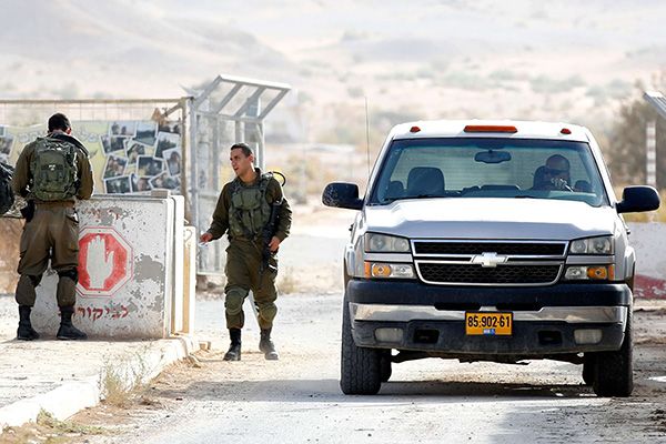 An Israeli farmer crosses the Israeli-Jordanian border as he returns from an Israeli plantation in Jordan after being checked by Israeli soldiers, at the Moshav Tsofar crossing point. (AFP)