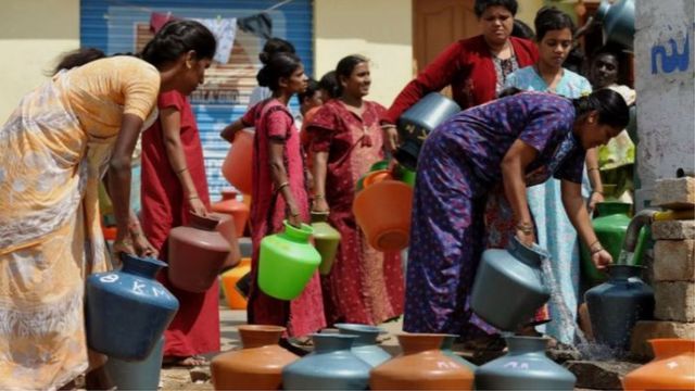 Indian women fill containers with water from a public tap