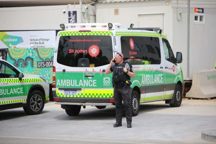 A paramedic stands in front of an ambulance.