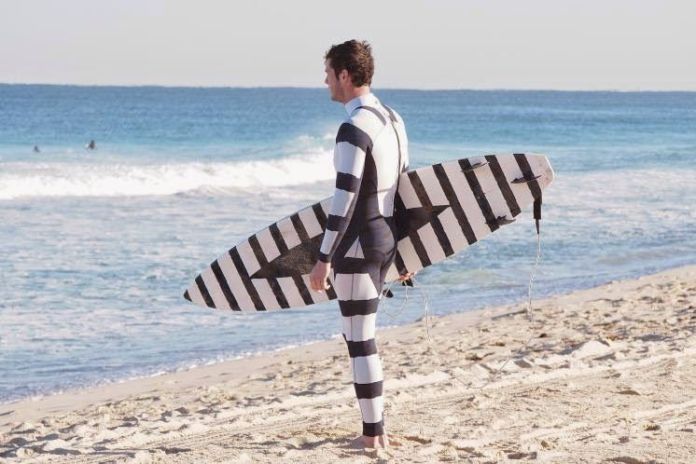 A surfer with a black and white wetsuit and a board.