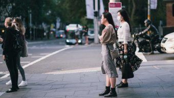 Women standing by a light on a street in Sydney.