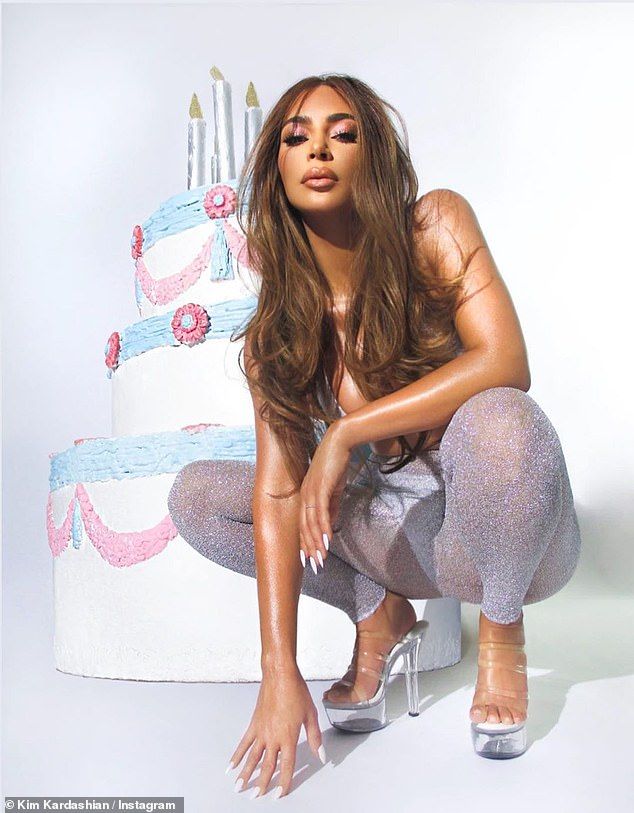 Sexy in silver: Kim showed off her caramel-colored locks while donning a silver bikini and sheer sparkling pants to advertise her birthday makeup
