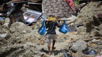 Seorang pria membawa sumur dari rumahnya yang terbalik di Balarola, Indonesia