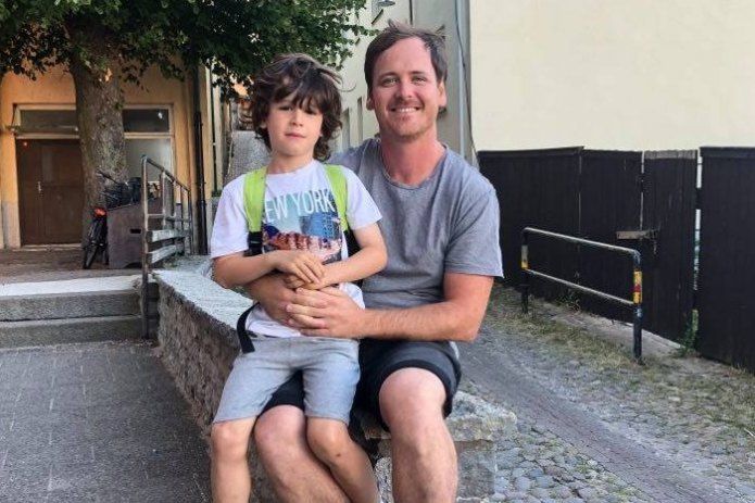 Clint Grundy and his son sit on his lap in Sweden.