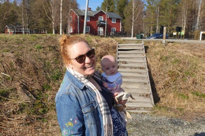 Wendy stands in the country holding her baby daughter.