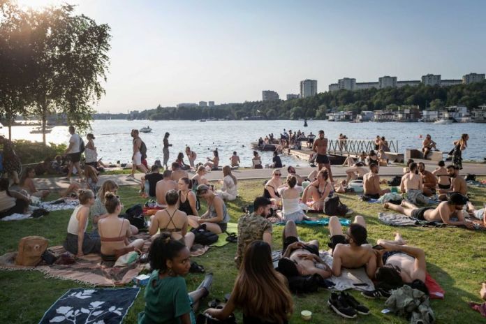 Swedes gather around a lake in the sun.