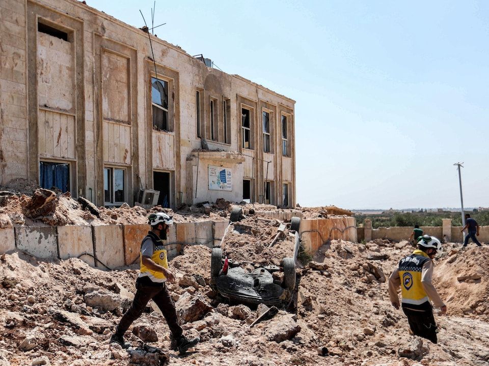 Syrians walk through the ruins of a building.