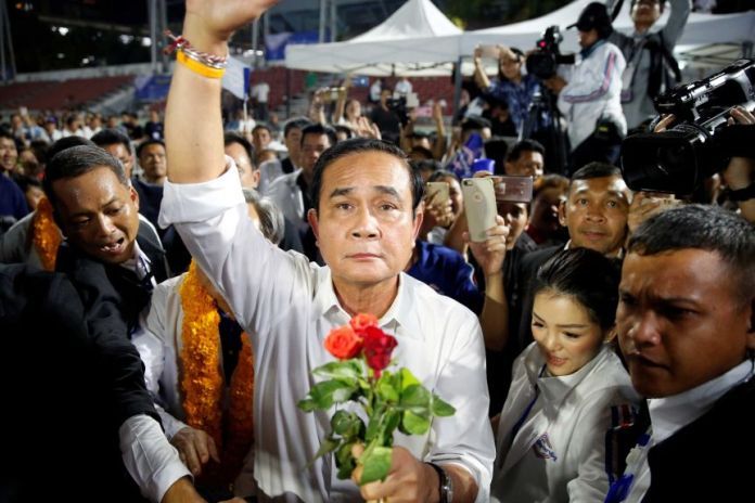 A man standing in a crowd clutching a bouquet of flowers