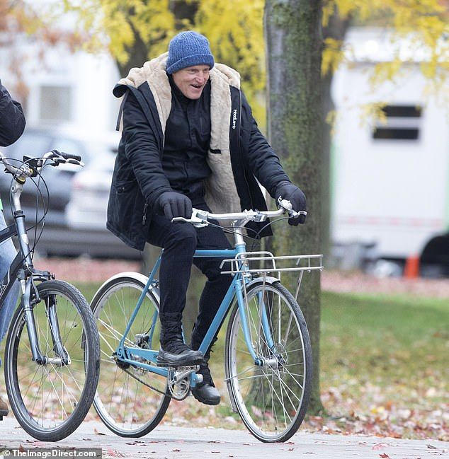 Bike tour: His co-star Harrelson, 59, was spotted on the set with a light blue bike but also stayed bundled up