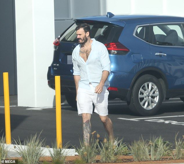 Casually cool: Meanwhile, Locky flashed his countless tattoos in an open blue linen shirt and white shorts, which he combined with white runners