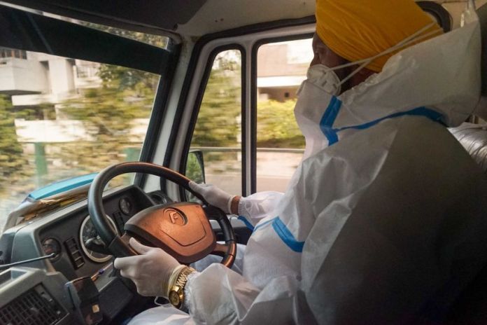A Sikh Indian in full PPE behind the wheel of a car