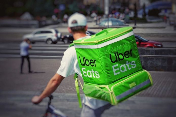 A man on a bike with a green Uber Eats backpack.