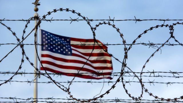 American flag behind a barbed fence on the US border with Mexico