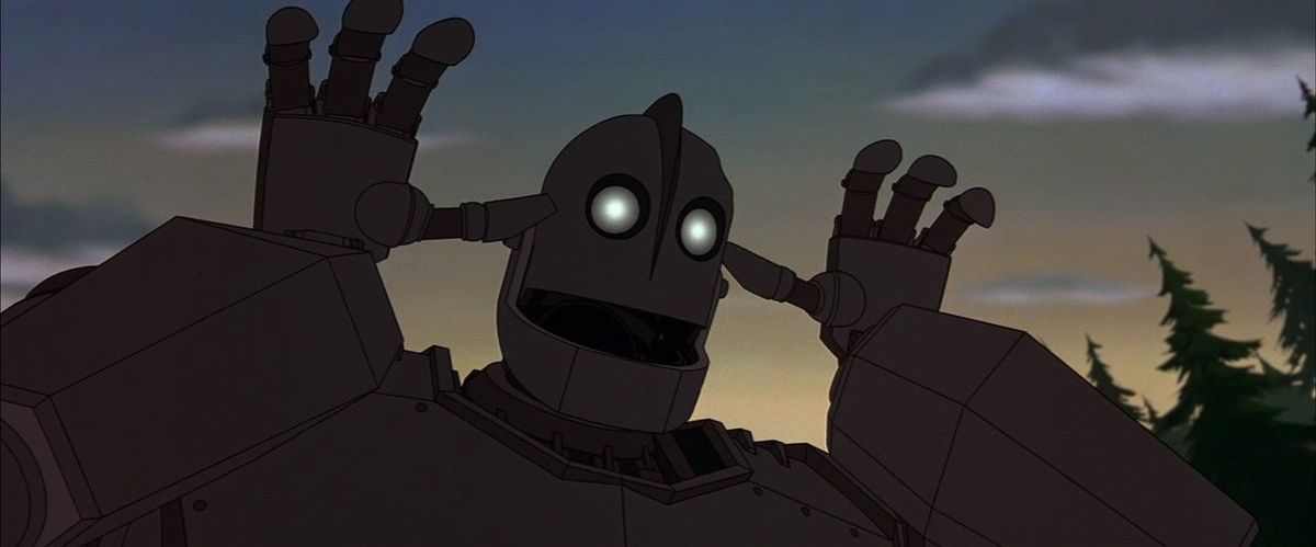 A huge gray robot with bright yellow eyes makes a goofy, goofy face and waves his hands near his head.