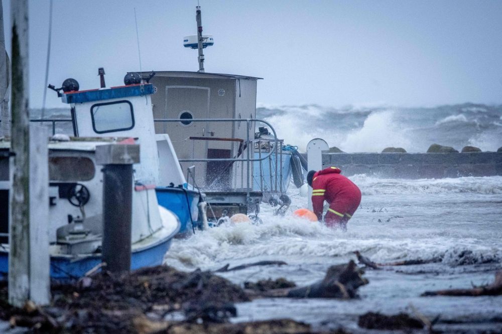 A sailor secures a boat as waves crash against the coast at Hesnaes harbor near Horbelev in Denmark on October 20, 2023, after a weather warning was issued for the area. — AFP pic