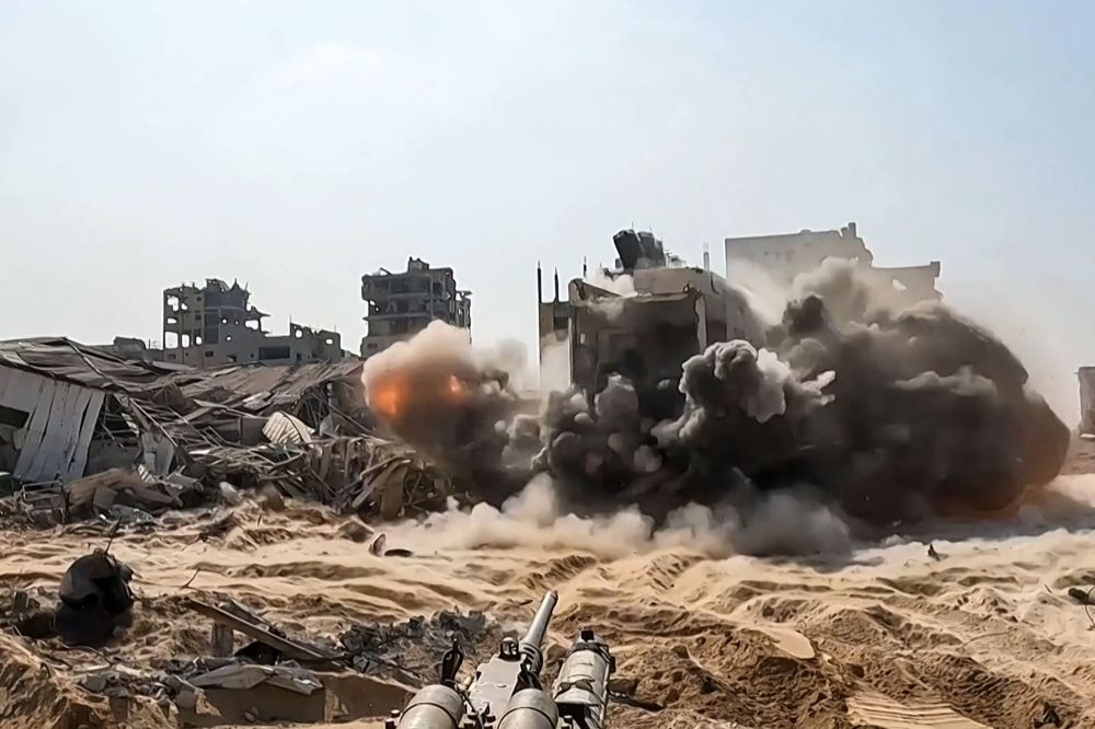 File photo from a handout video released by the Israeli army on November 11, 2023, shows an Israel gun firing at a building inside the Gaza Strip. ― AFP pic