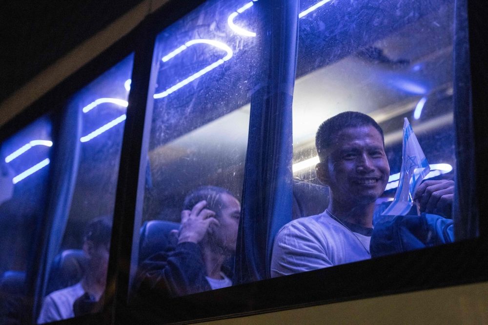 Thai nationals who were taken hostage by Hamas militants and recently released, wave from inside a bus as they leave the Shamir Medical Center near the city of Ramla, heading toward the airport to be flown home, on November 29, 2023. — AFP pic