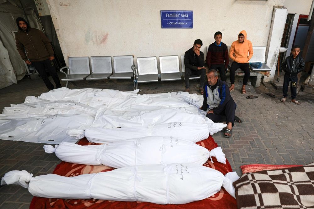 A Palestinian man sits beside shrouded corpses lined up at the al-Najjar hospital, following Israeli bombing on Rafah in the southern Gaza Strip on December 9, 2023, amid continuing battles between Israel and Hamas. — AFP pic