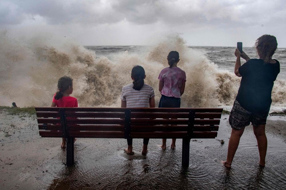 A family watch the storm roll in across the Coral Sea at Holloways Beach as Cyclone Jasper approaches landfall in Cairns in far north Queensland on December 13, 2023. — AFP pic