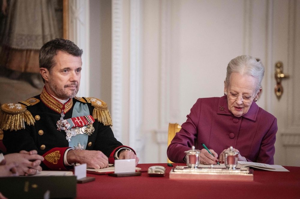 Queen Margrethe II of Denmark signs a declaration of abdication as King Frederik X of Denmark looks on in the Council of State at the Christiansborg Castle in Copenhagen, Denmark, on January 14, 2024.— AFP pic