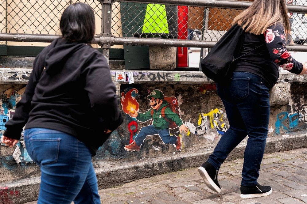 People walk by street art depicting video game character Luigi, and a crossed-out UnitedHealthcare logo, referencing Luigi Mangione, a suspect in the killing of UnitedHealth CEO Brian Thompson, at Pike Place Market in Seattle, Washington December 11, 2024. — Reuters pic