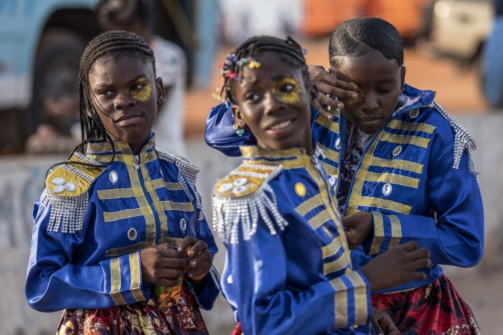 A reveller applies make up before lining up for their display at the children's parade on the first day of the Carnival in Luanda. — AFP pic