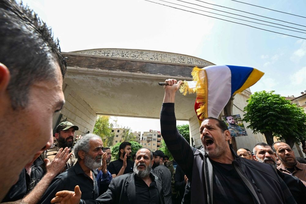 Members of Syria's Druze community wave flags and chant slogans during the funeral of seven people killed during overnight clashes with Syrian security forces, in Damascus, on April 30, 2025. — AFP pic
