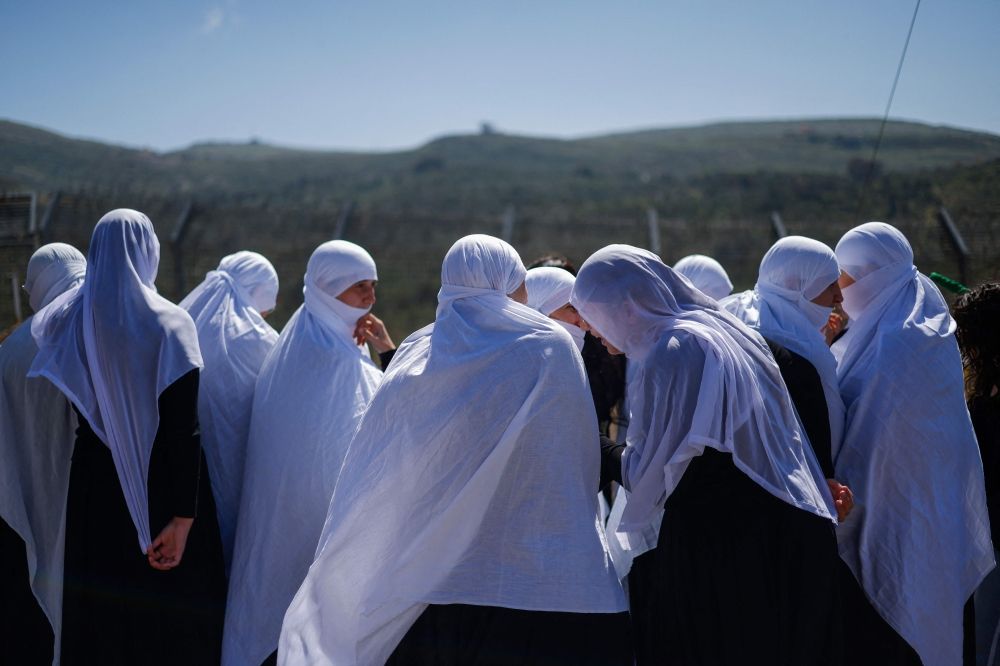 Druze women await the arrival of visitng Druze dignitaries fom Syria in a bus through a border barrier guarded by Israeli soldiers, near the village of Majdal Shams in the Israeli-annexed Golan Heights, on April 25, 2025. — AFP pic