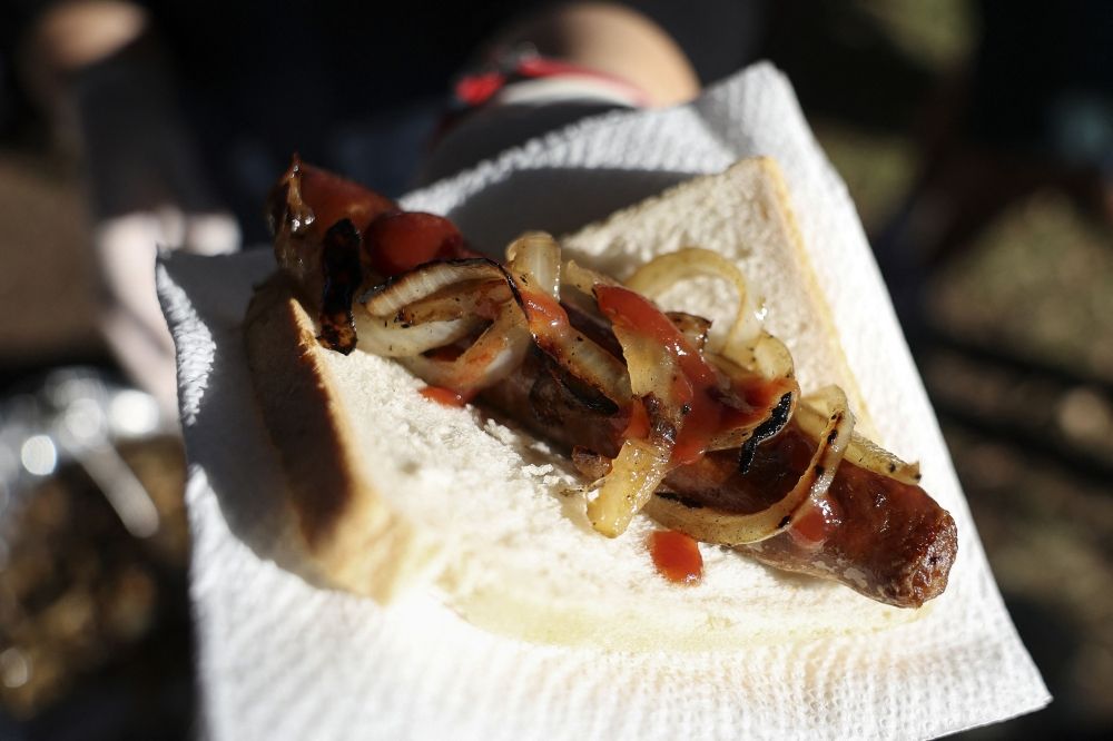 A volunteer hands out a sausage, known informally as