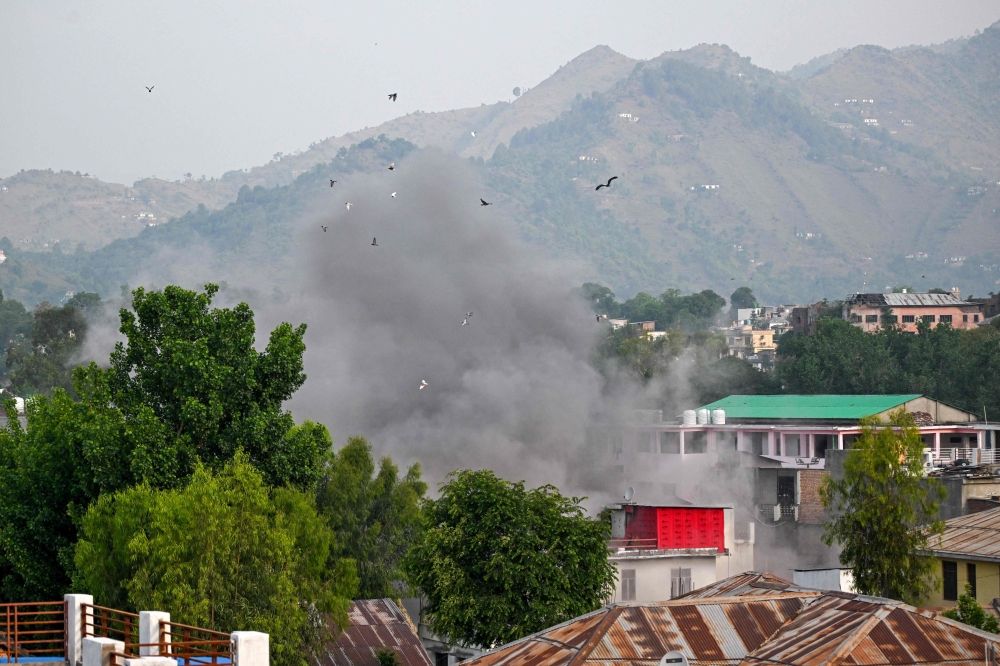 Smoke billows after an artillery shell landed in the main town of Poonch district in India's Jammu region today. — AFP pic