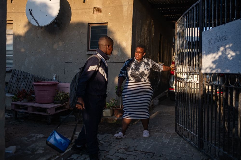 Eva Phaladi (right), the mother of Banele Phaladi (left), a student at the Kgololo Academy, opens the gate as he prepares to walk to school in Alexandra, near Johannesburg, on May 8, 2025. — AFP pic