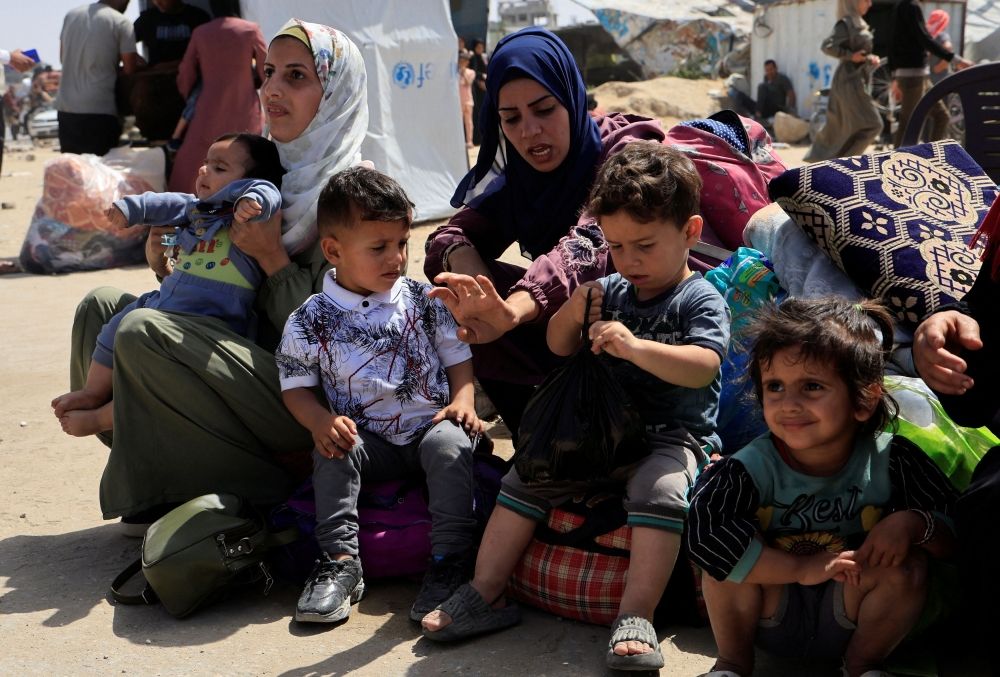 Palestinian women and children rest with their belongings as they flee their homes after the Israeli military issued orders for evacuation from eastern Khan Younis, in the southern Gaza Strip, May 19, 2025. — Reuters pic