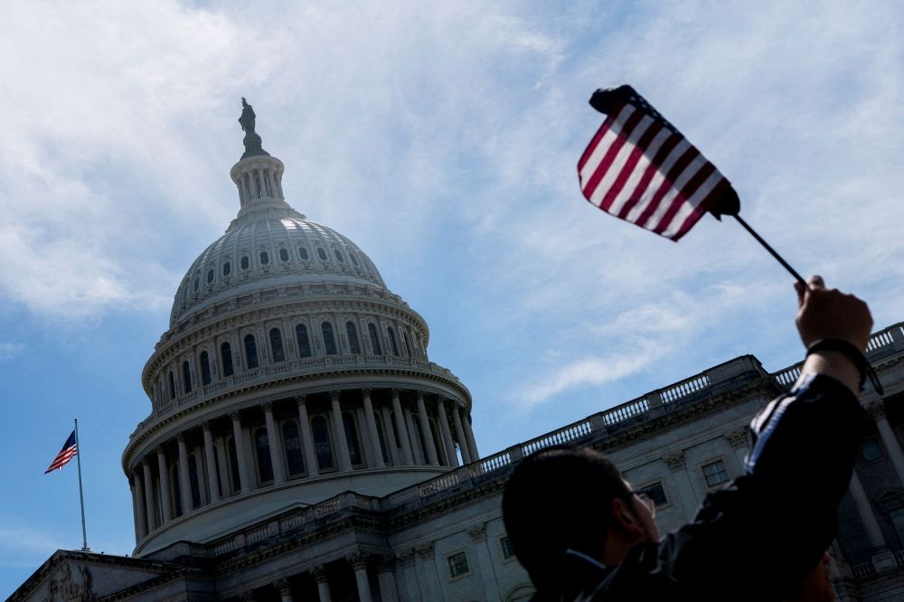 A visitor waves an American flag near the US Capitol, as the US House of Representatives considers US President Donald Trump’s sweeping tax-cut bill, on Capitol Hill in Washington, D.C. May 19, 2025. — Reuters pic