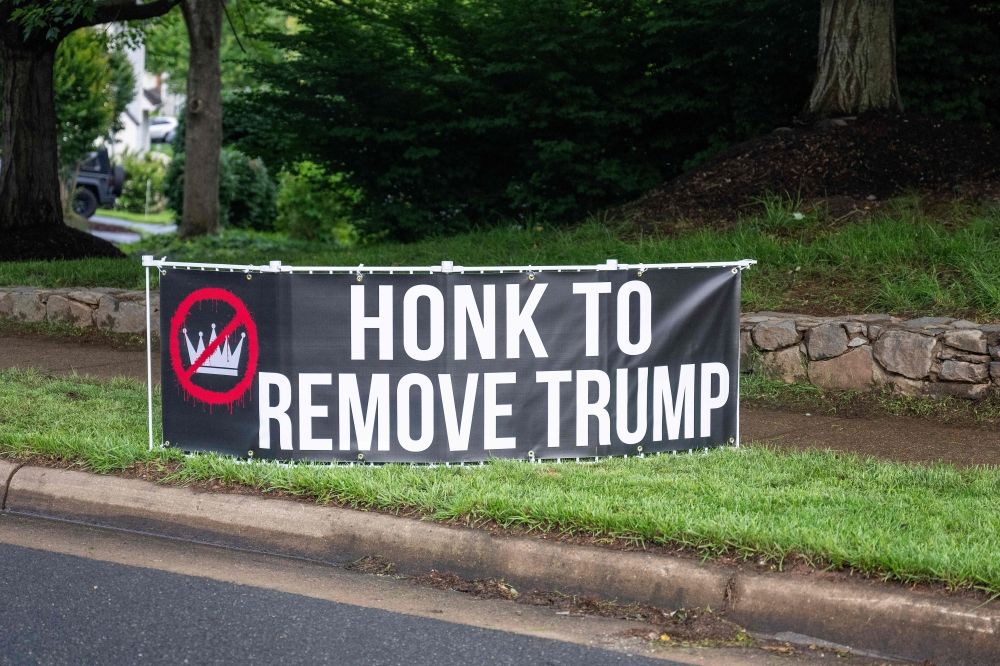 A placard against US President Donald Trump is seen outside Trump National Golf Course in Sterling, Virginia, on May 22, 2025. US President Donald Trump is attending a private dinner at his club for the top 220 buyers of his memecoin $TRUMP. — AFP pic