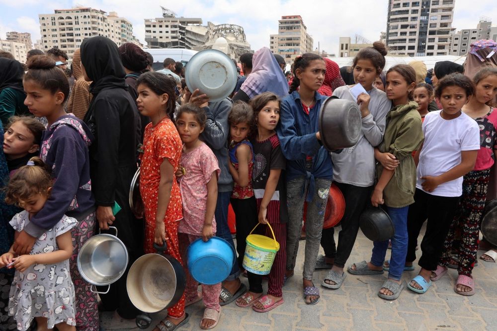 Palestinians, most of them children, queue in front of a hot meal distribution truck, at a displacement camp near Gaza City's port May 22, 2025. — AFP pic