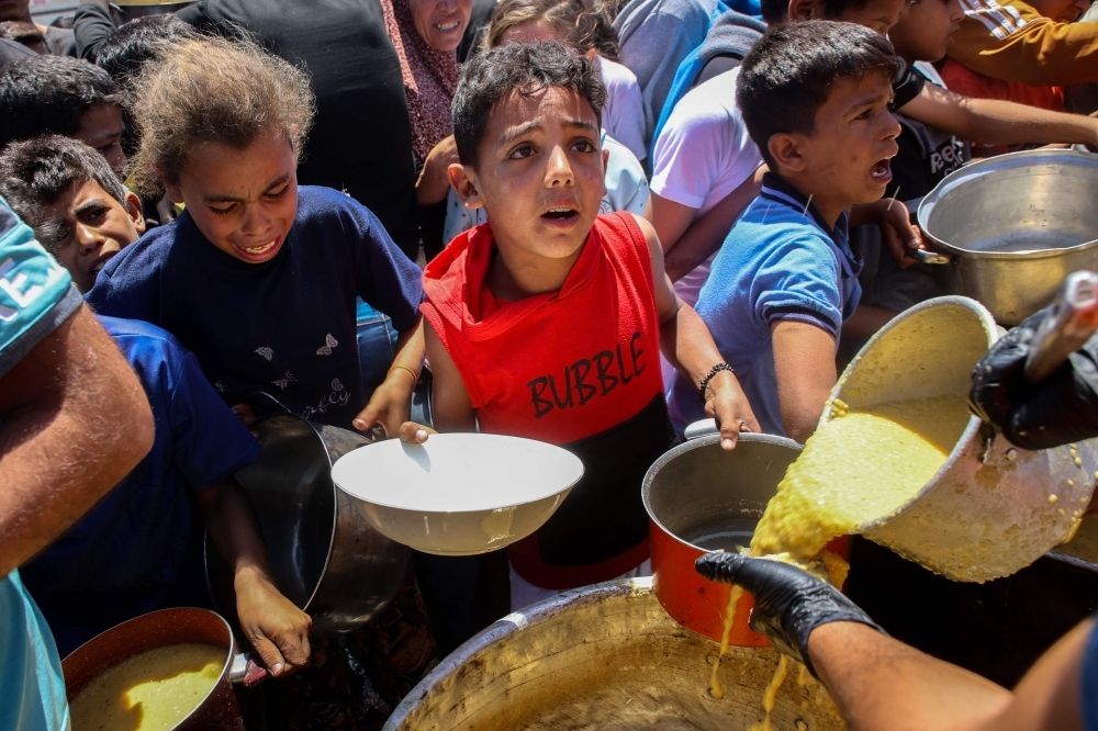 UN chief says Gaza enduring ‘cruellest phase’ of war as aid trucks looted and Israel’s strikes intensify Palestinians line up to receive a hot meal at a food distribution point in the Al-Rimal neighbourhood in Gaza City in the central Gaza Strip on May 21, 2025. — AFP pic