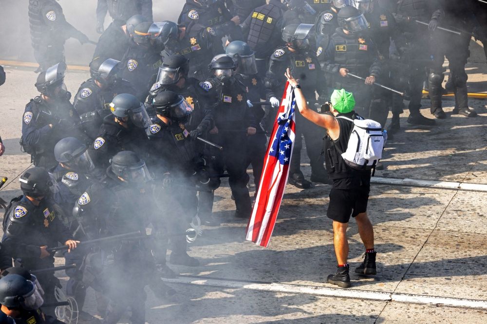 A demonstrator holds a US flag across from California Highway Patrol officers. — Reuters pic