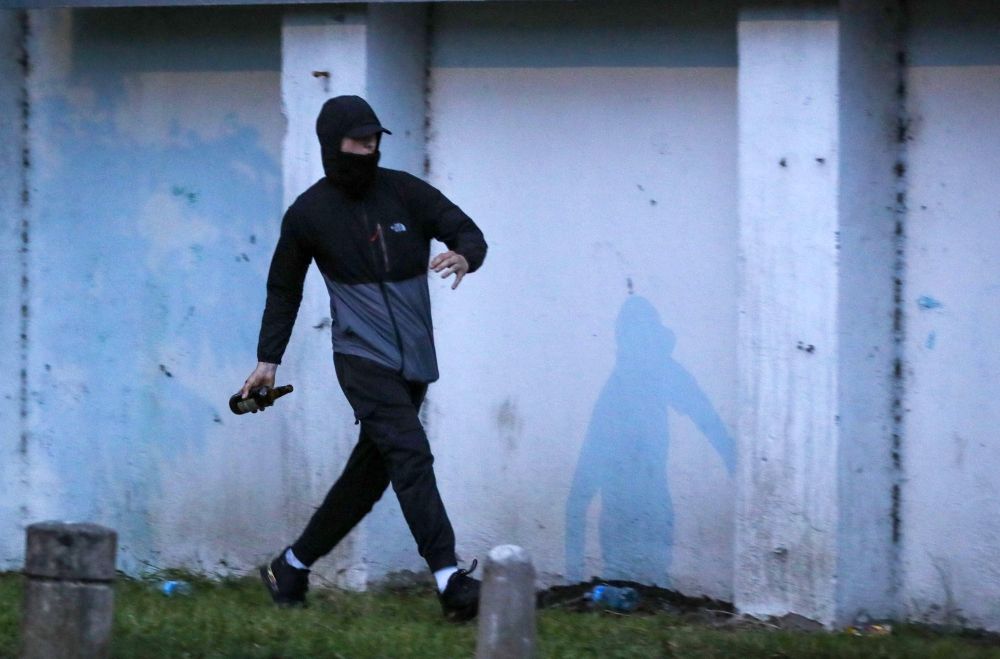 A masked protestor throws an item at Riot Police during a thrid night of anti-immigration demonstrations in Ballymena, Northern Ireland yesterday. — AFP pic